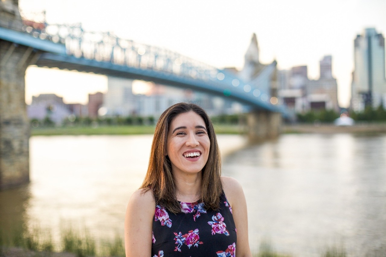 Mayra Guzman Sidler in front of the Robling Bridge and cincinnati skyline in background