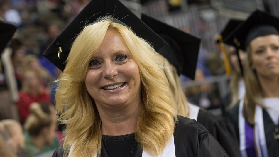 Adult student at commencement in cap and gown.